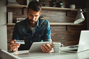 Young Man holding credit card and making online purchase